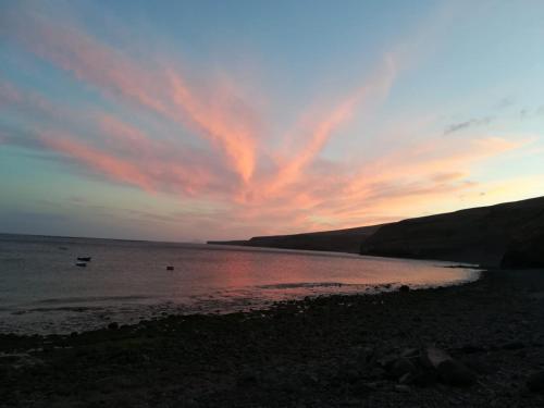 una puesta de sol sobre un cuerpo de agua con un cielo nublado en Apartamento Bienestar, en Playa Quemada