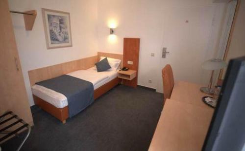 a hotel room with a bed and a desk at Hotel Savoy Bonn in Bonn