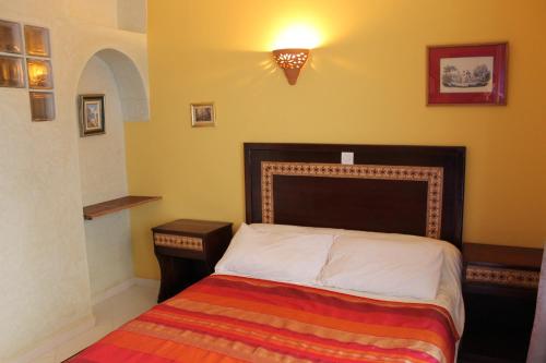 a small bedroom with a bed with a striped blanket at Dar Omar Khayam in Tangier