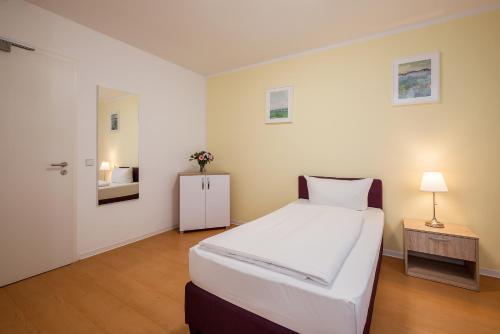 a bedroom with a large white bed and a table at Hotel City Green Berlin in Berlin