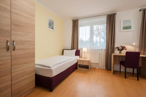 a hotel room with a bed and a desk and a window at Hotel City Green Berlin in Berlin