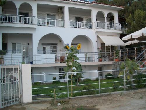 a large white building with balconies and a plant at Paschalia sea view studios in Psakoudia