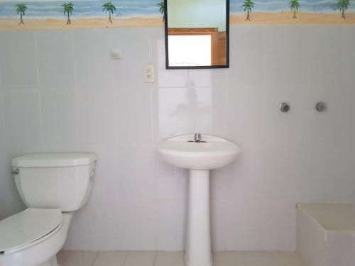 Un baño blanco con inodoro y lavabo. en El Eden Bungalows, en Mazunte