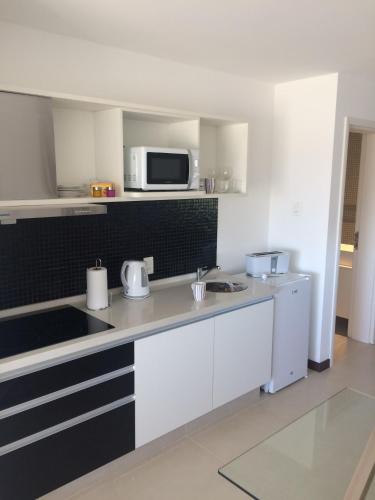 a kitchen with white cabinets and a microwave at Dos Orillas Monoambiente 412 in Colonia del Sacramento
