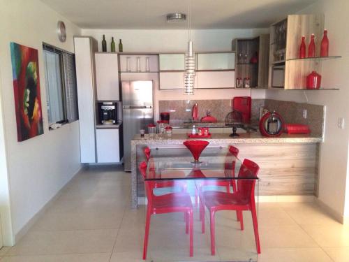a kitchen with a glass table and red chairs at HOTEL CANARIUS DE GRAVATA - Flat in Gravatá
