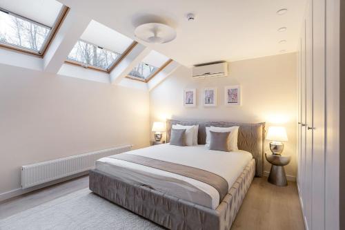 um quarto com uma cama com paredes brancas e clarabóias em Luxury for everyone - Hills Park Lux Apartments 1 em Vilnius