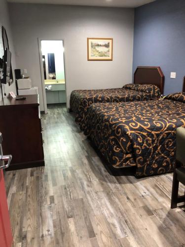 a hotel room with two beds and a desk at Delux Inn Cleburne in Cleburne
