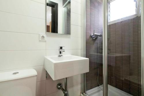 La salle de bains blanche est pourvue d'un lavabo et d'une douche. dans l'établissement Putxet by gaiarooms, à Barcelone