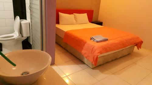 a bathroom with a bed and a sink and a toilet at HOTEL SEGARA MANDALA in Negara