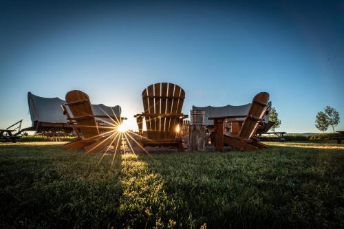 a row of chairs sitting on top of a grass covered field at Conestoga Ranch Glamping Resort in Garden City