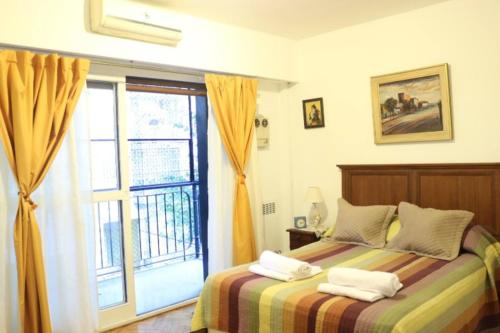 1 dormitorio con 1 cama con toallas en Confortable dpto ,100 m2, cochera en el edificio gratis , balcon grande a la calle, cerca MOVISTAR ARENA en Buenos Aires