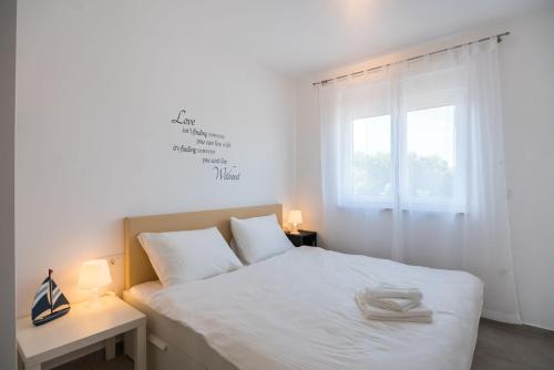 a bedroom with a bed with white sheets and a window at Apartments Residence Romance in Pinezici