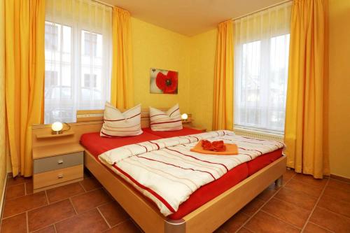 a bedroom with a large bed with two windows at Haus Clara Wohnung 02 in Ostseebad Koserow