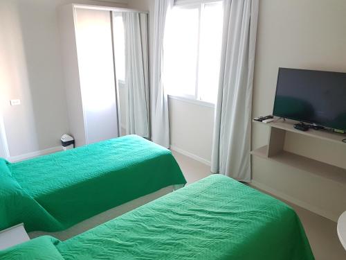 a room with two green beds and a flat screen tv at MitreCity in Ostende