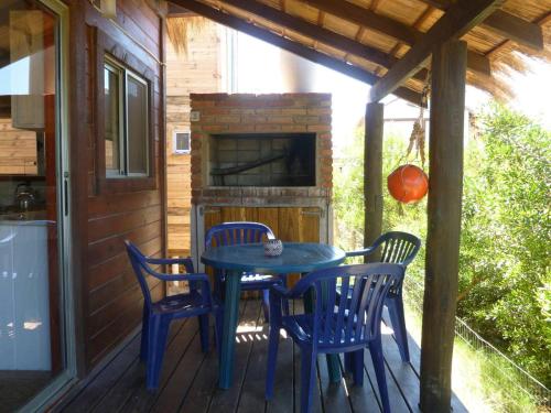 una mesa azul y sillas en un porche con chimenea en Excelente Cabaña Cumbre del Diablo 2, en Punta del Diablo