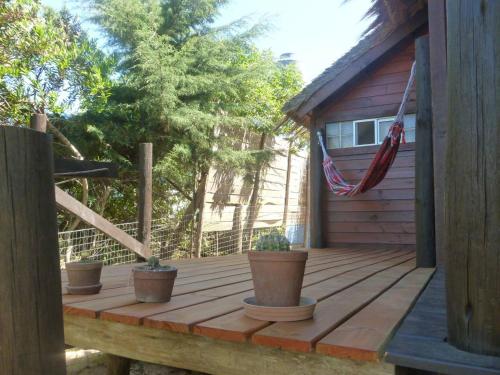 a wooden deck with potted plants and an american flag at Excelente Cabaña Cumbre del Diablo 2 in Punta Del Diablo