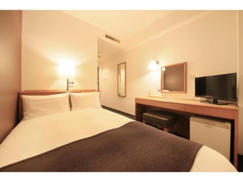 東京にあるスマイルホテル東京綾瀬駅前のベッド、デスク、テレビが備わるホテルルームです。