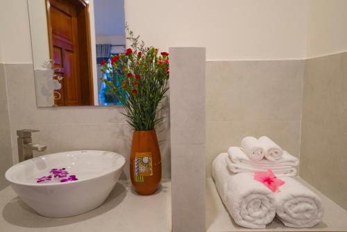 a bathroom with a sink and a vase with flowers at An Bang Star Homestay in Hoi An