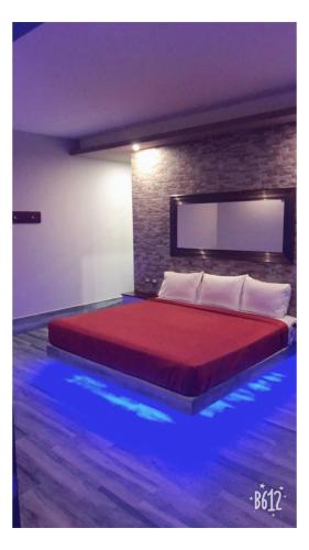 a bedroom with a large red bed with blue lights at Hotel Plaza Arteaga in Monterrey