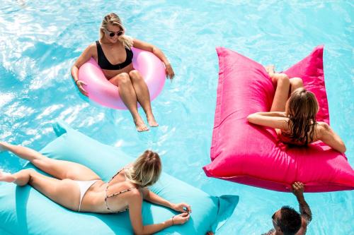 a group of women sitting on inflatables in a swimming pool at Kos One Hostel in Canggu