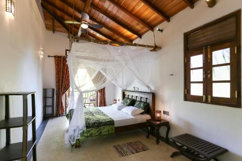 a bedroom with a bed with a mosquito net at Annavilla in Tangalle