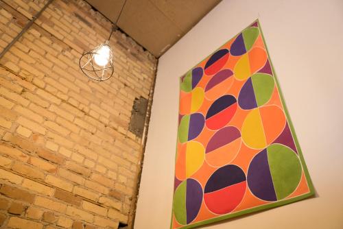 a colorful painting hanging on a wall next to a brick wall at Hostel du Nord in Duluth