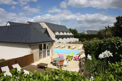 a swimming pool with chairs and a table next to a house at L'Hippocampe in Plouharnel