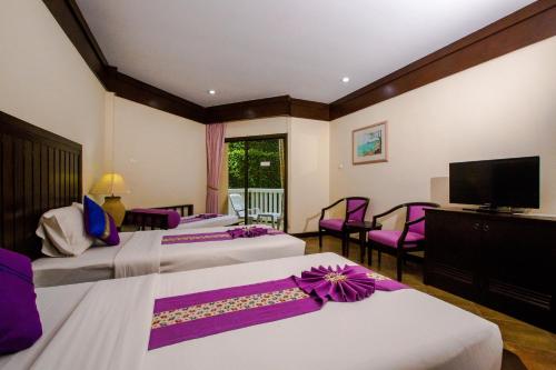 a hotel room with three beds and a flat screen tv at Kata Poolside Resort SHA Extra Plus in Kata Beach