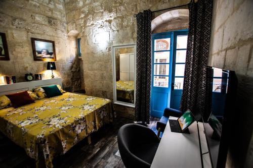 una camera da letto con un letto, una sedia e una finestra di Cosy Townhouse in Historic Centre a Birgu (Vittoriosa)