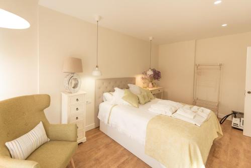 sypialnia z białym łóżkiem i krzesłem w obiekcie ELIA’S HOME. w mieście Ourense