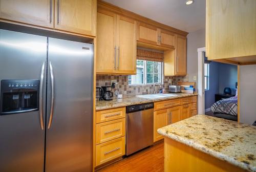 a kitchen with a stainless steel refrigerator and wooden cabinets at Stylish 2 Bed & 2 Bath at the Heart of Hollywood with Free Parking - One Car only in Los Angeles