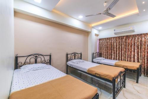a bedroom with two beds and a ceiling fan at Nest Dormitory in Mumbai
