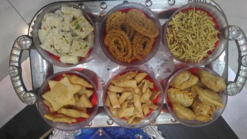 um grupo de quatro recipientes de diferentes tipos de alimentos em Ashta Lakshmi Tourist Home Stay em Indore