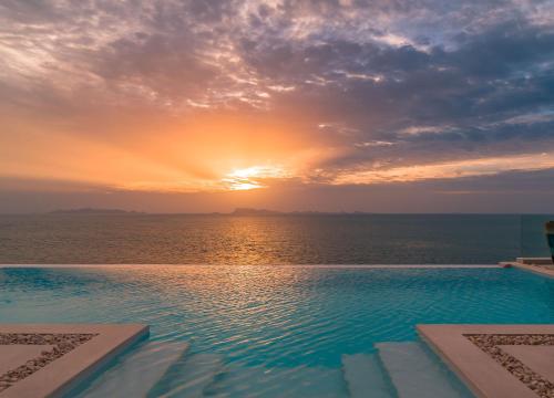 a swimming pool with a sunset over the ocean at Fabuleuse villa Alizés vue mer, avec Staff et véhicule 4x4 in Ban Bang Po