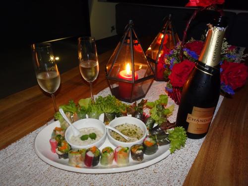 a plate of food on a table with a bottle of wine at Fabuleuse villa Alizés vue mer, avec Staff et véhicule 4x4 in Ban Bang Po