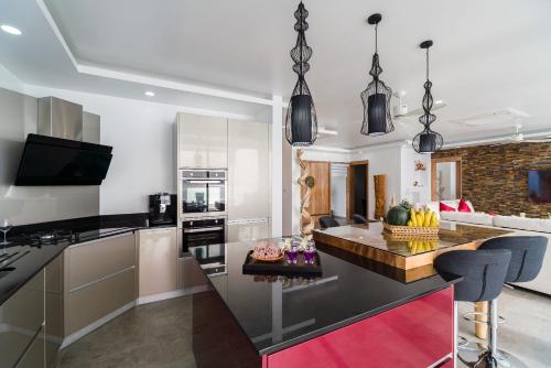 a kitchen with a counter top and a living room at Fabuleuse villa Alizés vue mer, avec Staff et véhicule 4x4 in Ban Bang Po