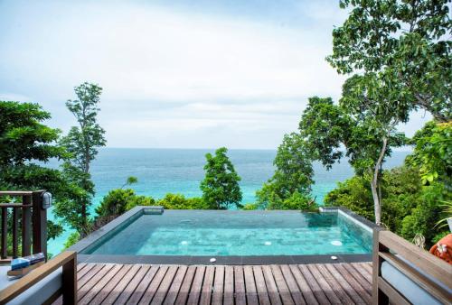 a swimming pool on a deck with the ocean in the background at Serendipity Beach Resort Koh Lipe in Ko Lipe