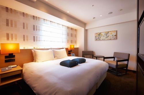 a hotel room with a large white bed and chairs at Hotel Forza Nagasaki in Nagasaki