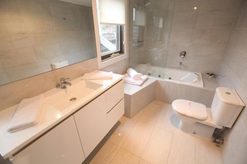 a bathroom with a toilet and a sink and a tub at Points South By The Sea in Apollo Bay