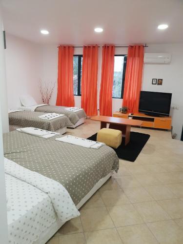 a room with two beds and a desk with a television at Нощувки Шумен in Shumen