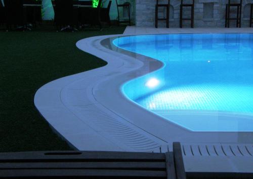 a swimming pool with a path around it at night at Anna Platanou Hotel in Parikia