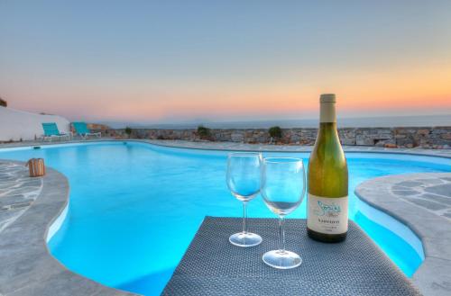 - une bouteille de vin et deux verres à côté de la piscine dans l'établissement Villa Livana Naxos, à Kastraki Naxou