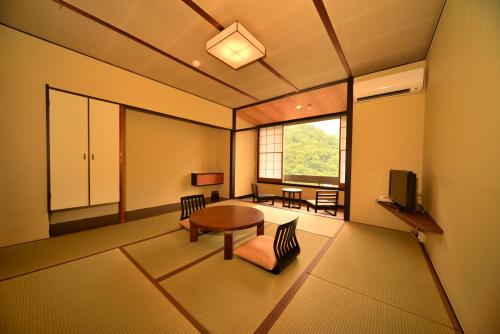a living room with a table and chairs and a window at Hatago Kintoen in Hakone