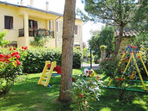 einen Hof mit einem Spielplatz und einem Baum in der Unterkunft Agriturismo La Ginestrella in Civitella D'Arna