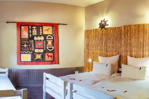 a bedroom with two beds and a painting on the wall at Chameleon Backpackers & Guesthouse in Windhoek