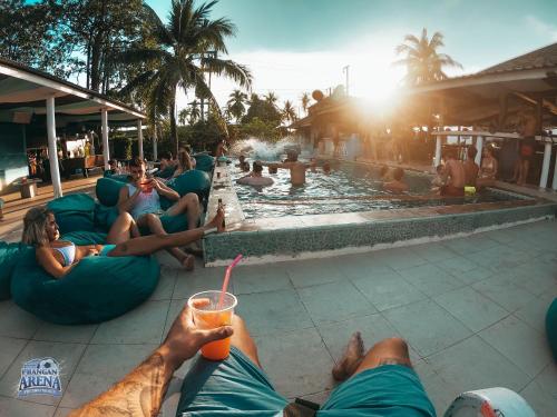 un groupe de personnes se posant sur des poufs au bord d'une piscine dans l'établissement Phangan Arena Hostel, à Baan Tai