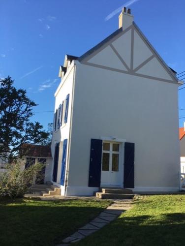 une maison blanche dotée de portes bleues et d'une pelouse. dans l'établissement Villa Les Abeilles - Wimereusienne, à Wimereux