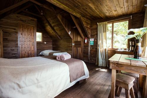 a bedroom with two beds in a wooden cabin at Paraíso Quetzal Lodge in Tres de Junio