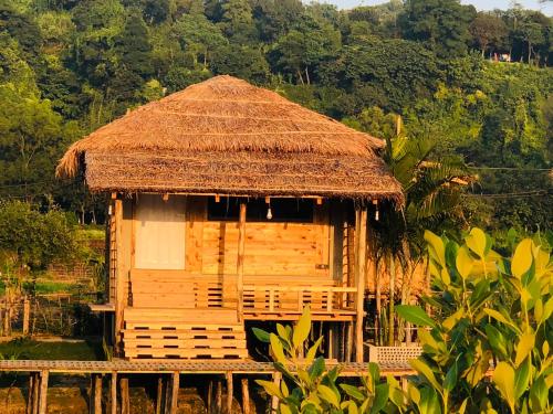 a hut with a straw roof on a field at Moon Nest in Dhoāpālong