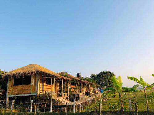 a house with a straw roof with people standing outside at Moon Nest in Dhoāpālong